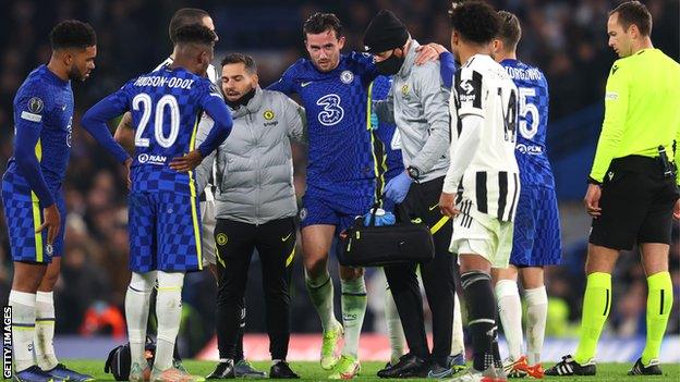 Chelsea's Ben Chilwell is aided off the pitch by two physios