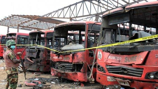 A soldier standing guard in front of burnt buses after an attack blamed on Boko Haram in Abuja, Nigeria - 14 April 2014