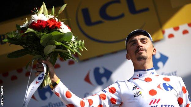 Julian Alaphilippe raises a bouquet of flowers to celebrate winning stage 10