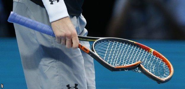 Andy Murray of Britain carries his smashed racquet back to his seat as he plays against Stan Wawrinka of Switzerland in their singles tennis match