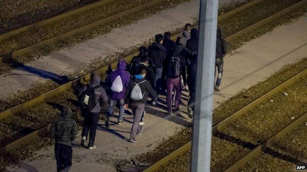 Migrants walking along rail tracks towards the Channel Tunnel