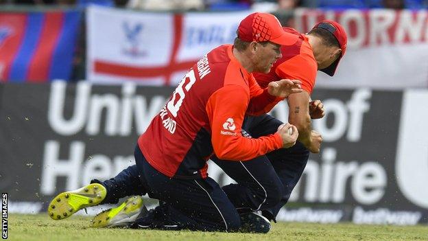 England captain Eoin Morgan holds on to a high catch despite colliding with Tom Curran