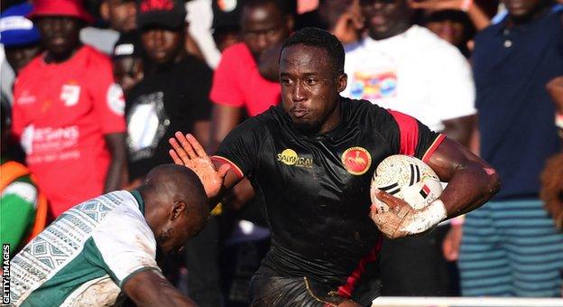 Uganda's Munyani Ian tries to stop a player while carrying the ball against Zimbabwe