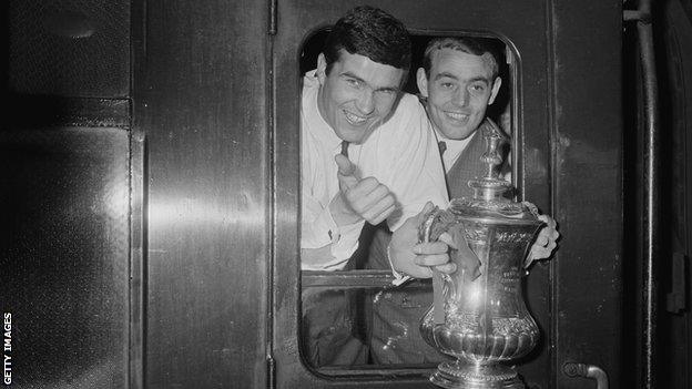 Liverpool captain Ron Yeats (left) St John show off the 1965 FA Cup trophy from the train that will take them from Euston back to Liverpool