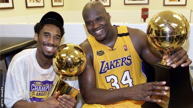 Kobe Bryant (L) of the Los Angeles Lakers holds the Larry O'Brian trophy as team-mate Shaquille O'Neal holds the MVP trophy after winning the NBA Championship against Indiana Pacers 19 June, 2000, after game six of the NBA Finals at Staples Center in Los Angeles, CA.