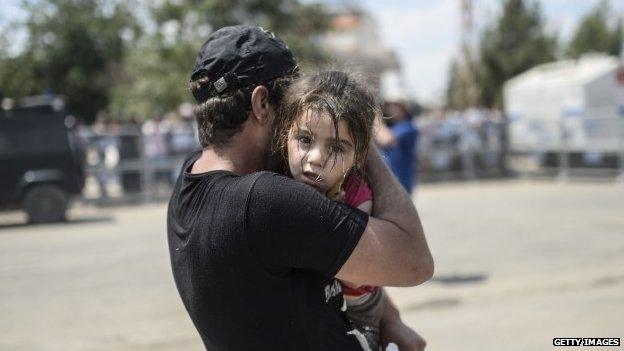 A Syrian man fleeing the war arrives in Turkey with his child at the Akcakale border crossing