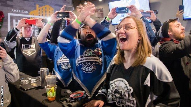 Ice hockey fans celebrate the announcement of Seattle being awarded an NHL expansion franchise in a bar in the city