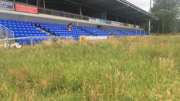 A scene of dereliction as long weeds grow in front of the main stand at the Riverside Stadium