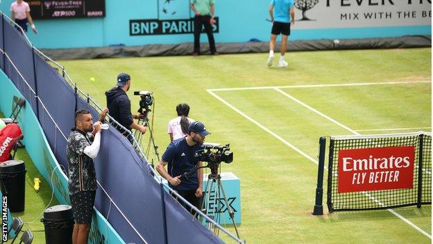 Kyrgios looks over a fence at the next court