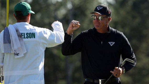 Phil Mickelson bumps fists with his caddie at the Masters