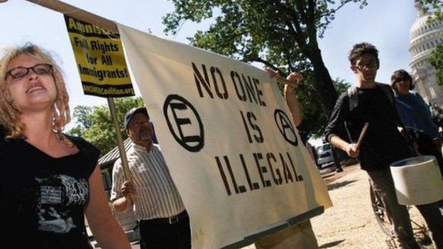 Protesters holding a sign reading 'no one is illegal'