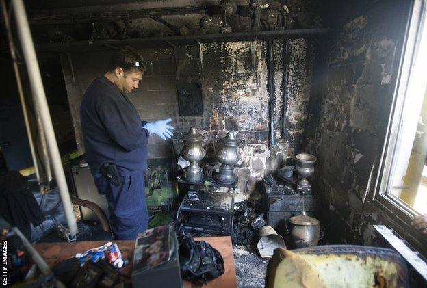 A policeman examines the scene after a fire at Beitar in February 2013. Police said arsonists torched the club offices over the signing of two Muslim footballers from Chechnya