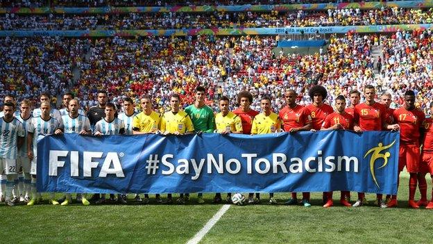 Argentina and Belgium players and referees pose with a banner before a World Cup game in 2014