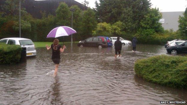 People wade in water in a car park