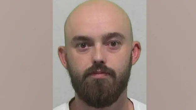 A mugshot of of Kieran Usher who is bald with a full brown beard.