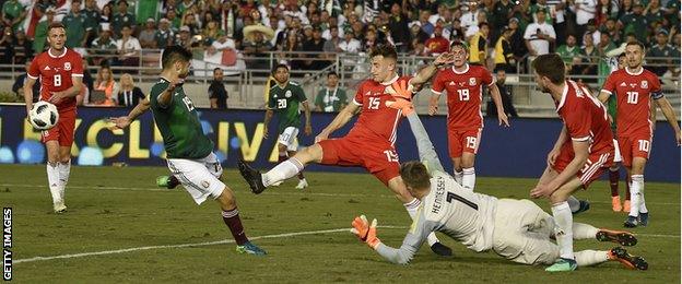 Action shot of Wayne Hennessey making a save as Wales scramble the ball clear