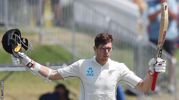 New Zealand all-rounder Mitchell Santner takes his helmet off and raises his bat to celebrate his century on day four of the first Test against England