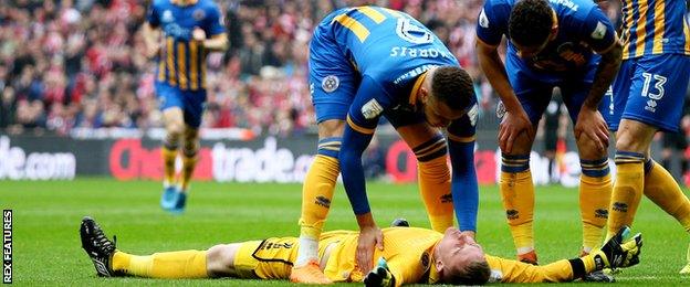 Shrewsbury goakleeper Dean Henderson on the floor after his collision with Lincoln's Matt Rhead