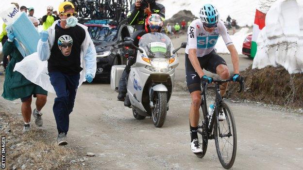 Spectators wearing surgical masks and carrying a giant inhaler run alongside Chris Froome during his Giro d'Italia win in May