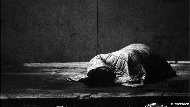 Sleeping rough - a person hidden by a sleeping bag on the street in a black and white image