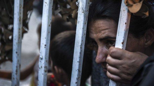 Migrants are seen behind a fence as they arrive at the refugee center in the town of Presevo, after walking from Macedonia to Serbia.