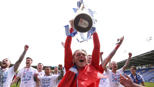 Thelo Aasgaard of Wigan Athletic celebrates with the League One trophy