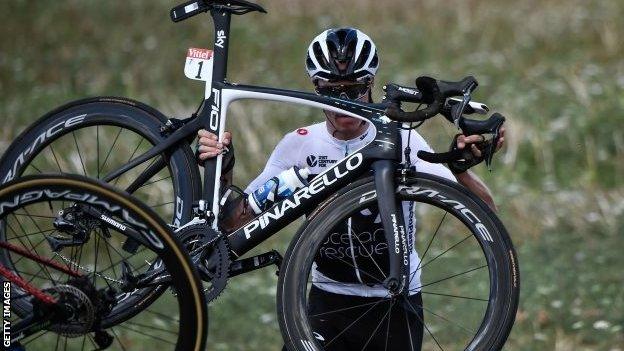 Chris Froome lifts his bike back on to the road after crashing on stage one