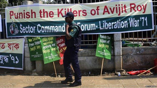 Police officer walks past banner calling for justice for Avijit Roy