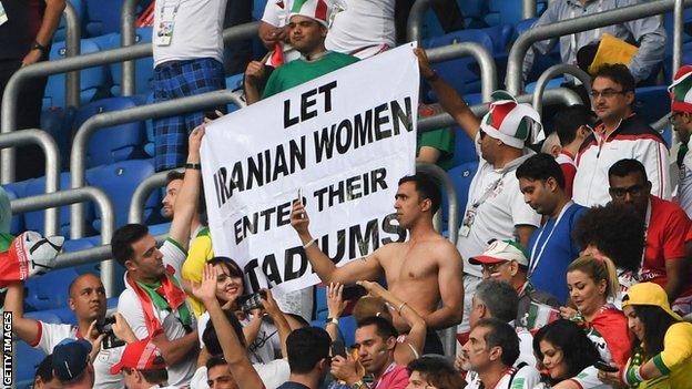 A campaign group holds up a banner saying "Let Iranian women enter their stadiums" at a match between Morocco and Iran at the 2018 World Cup