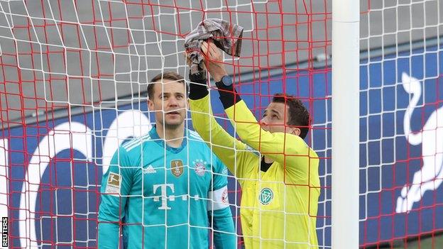 The assistant referee uses Manuel Neuer's towel to try and fix a hole in the net