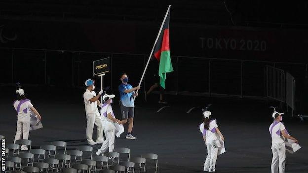 A volunteer carries the Afghanistan flag into the National Stadium in Tokyo