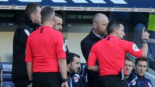 Keith Stroud speaks with both managers during a halt in Millwall's win against Reading