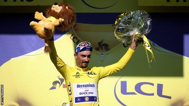 Julian Alaphilippe raises his hands in celebration on the podium after winning stage 13 of the 2019 Tour de France