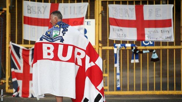 Bury fan stands at the gates of Gigg Lane