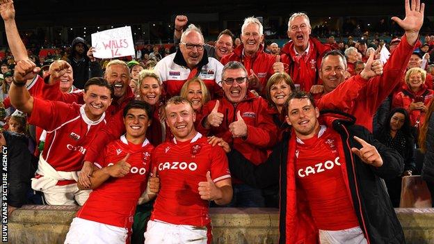 Wales players Louis Rees-Zammit, Tommy Reffell and Ryan Elias celebrate with supporters