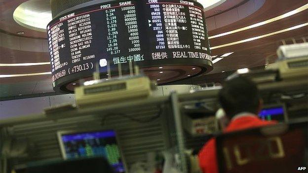 A trader (R) works at the Hong Kong Stock Exchange on July 9, 2015.