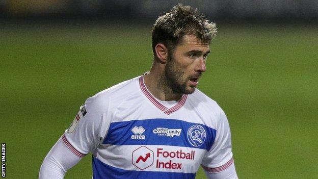 QPR striker Charlie Austin, wearing the club's 2020-21 home shirt with the Football Index company name and logo in red on the white and blue hoops