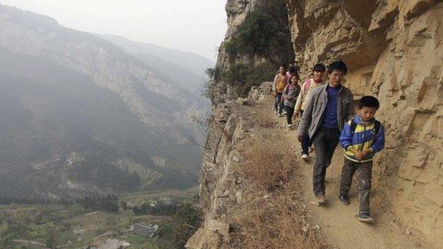 Students walking to school on narrow paths along the side of a mountain in China