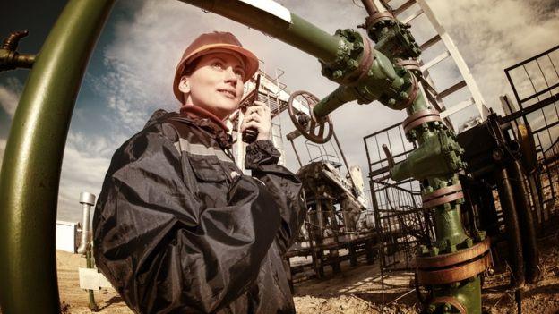 Image of a woman listening to a walkie-talkie, looking into the distance on a construction site.