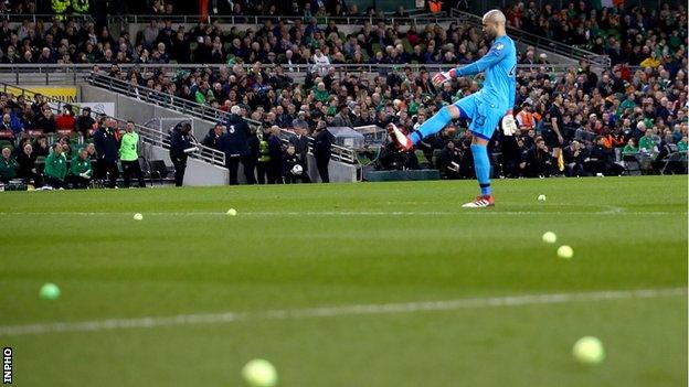 Republic keeper Darren Randolph helps clear the tennis balls from the Aviva pitch