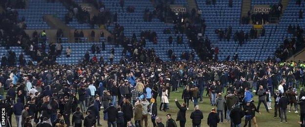 Coventry City fans celebrate on the pitch after the final whistle