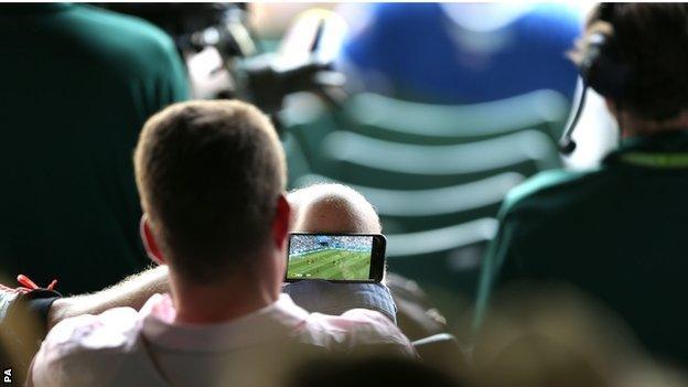 Tennis fan at Wimbledon watching England v Sweden on his phone