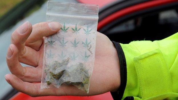 A police officer holds a small bag of cannabis