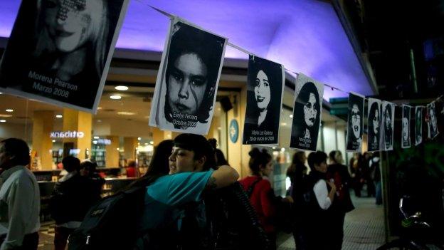 Two women embrace under pictures of victims of gender violence during a demonstration demanding policies to prevent femicides in Buenos Aires