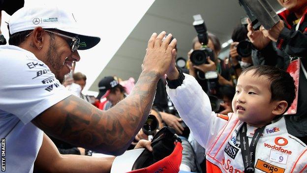 Lewis Hamilton high-fives a young fan at the Suzuka circuit in the lead-up to the Japanese Grand Prix