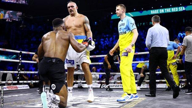 Oleksandr Usyk helps Anthony Joshua to his feet