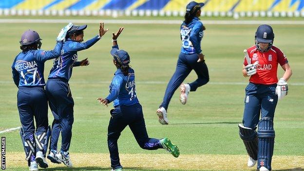 Sri Lanka players celebrate as England's Lauren Winfield walks off the pitch after being run out