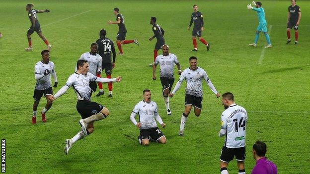 Swansea players celebrate with Conor Hourihane as Brentford protest following his goal against the Bees in January