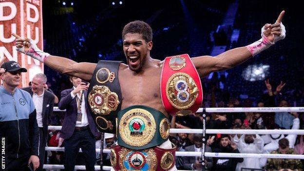 Anthony Joshua celebrates a win with his heavyweight belts