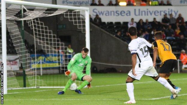 Wayne Routledge shoots through the legs of Cambridge goalkeeper Callum Burton to score Swansea's sixth goal